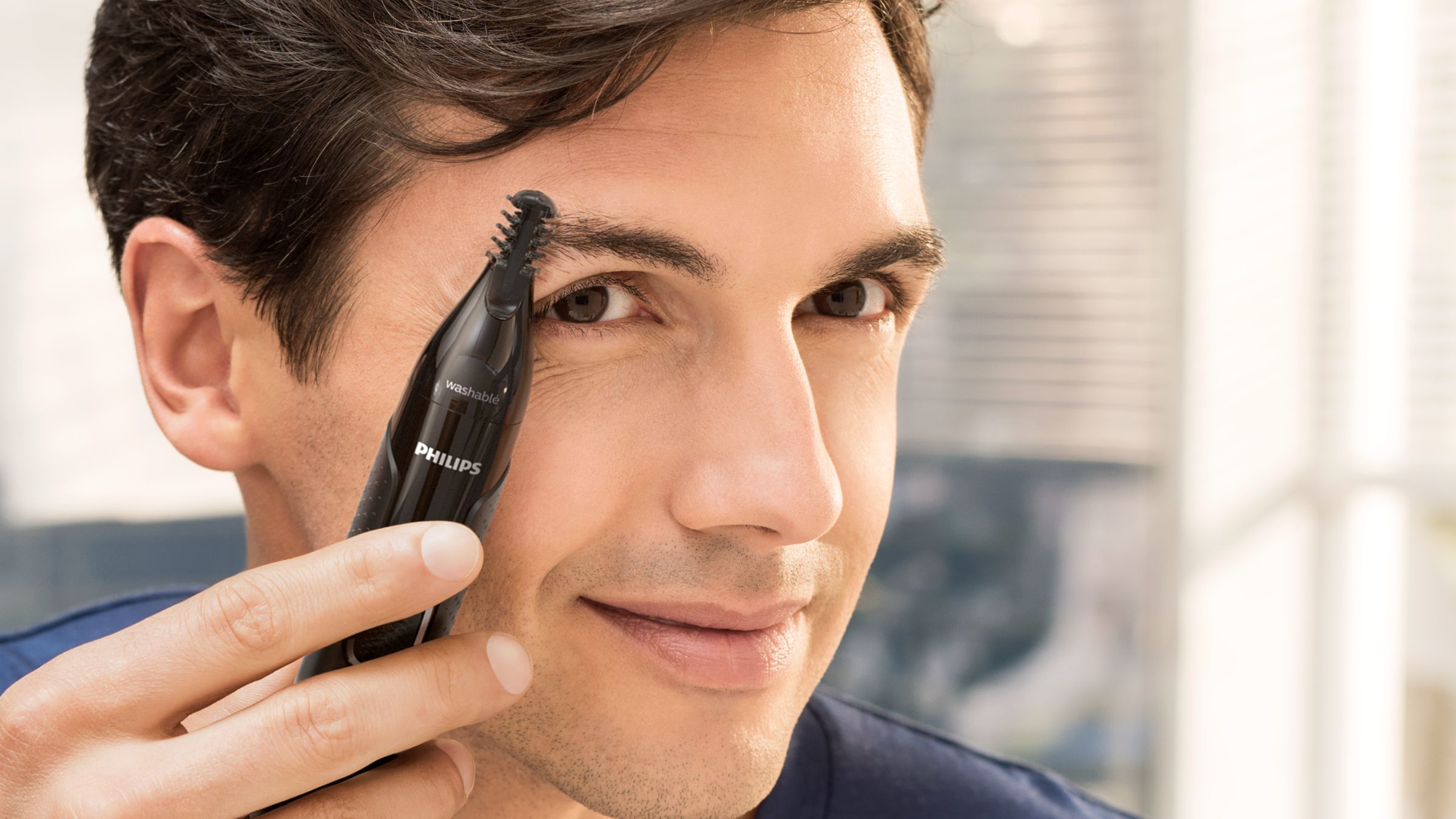 Man die een Philips neushaartrimmer op zijn wenkbrauw gebruikt.