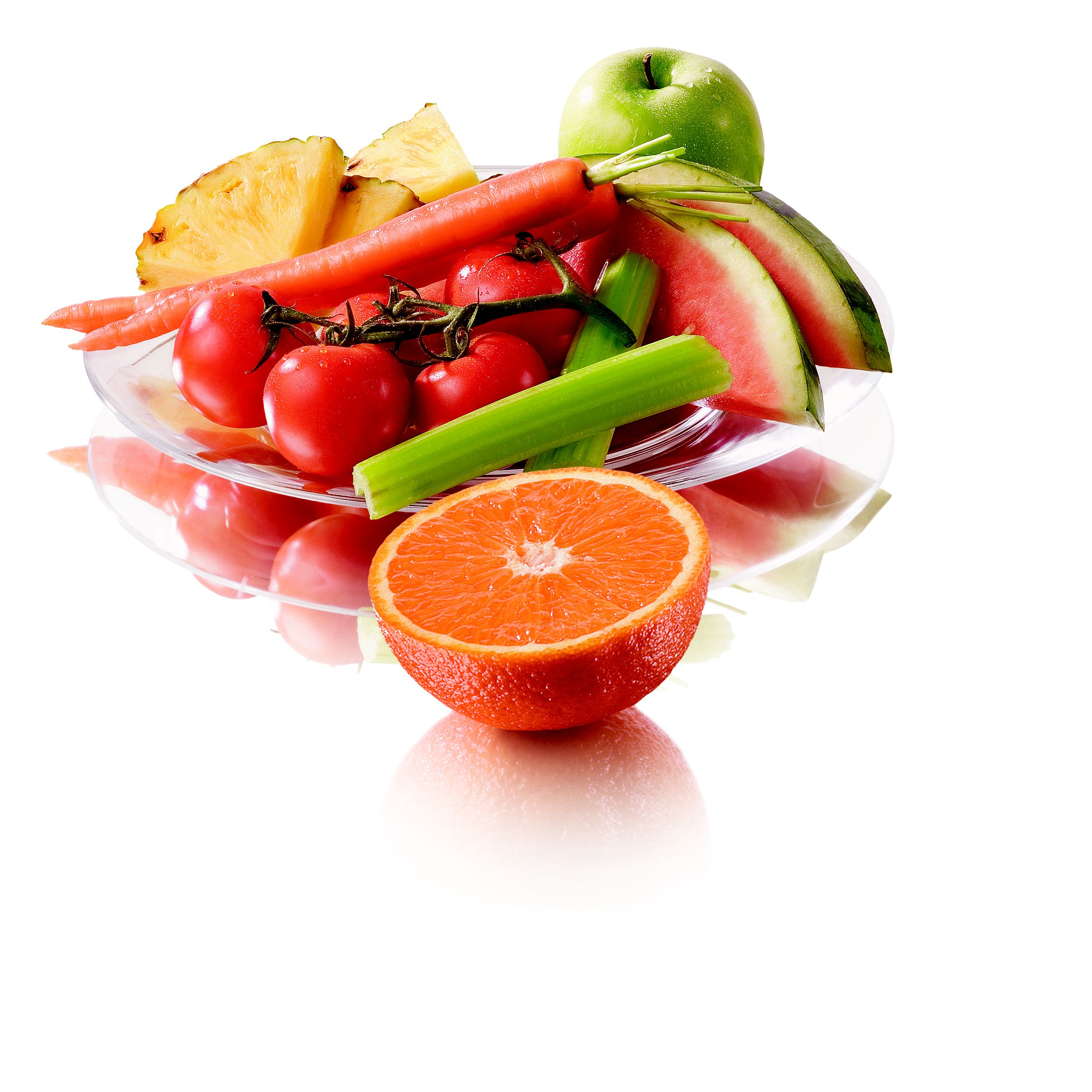 Ananas, tomaten, wortelen, selderij, appel en sinaasappel in een glazen kom.