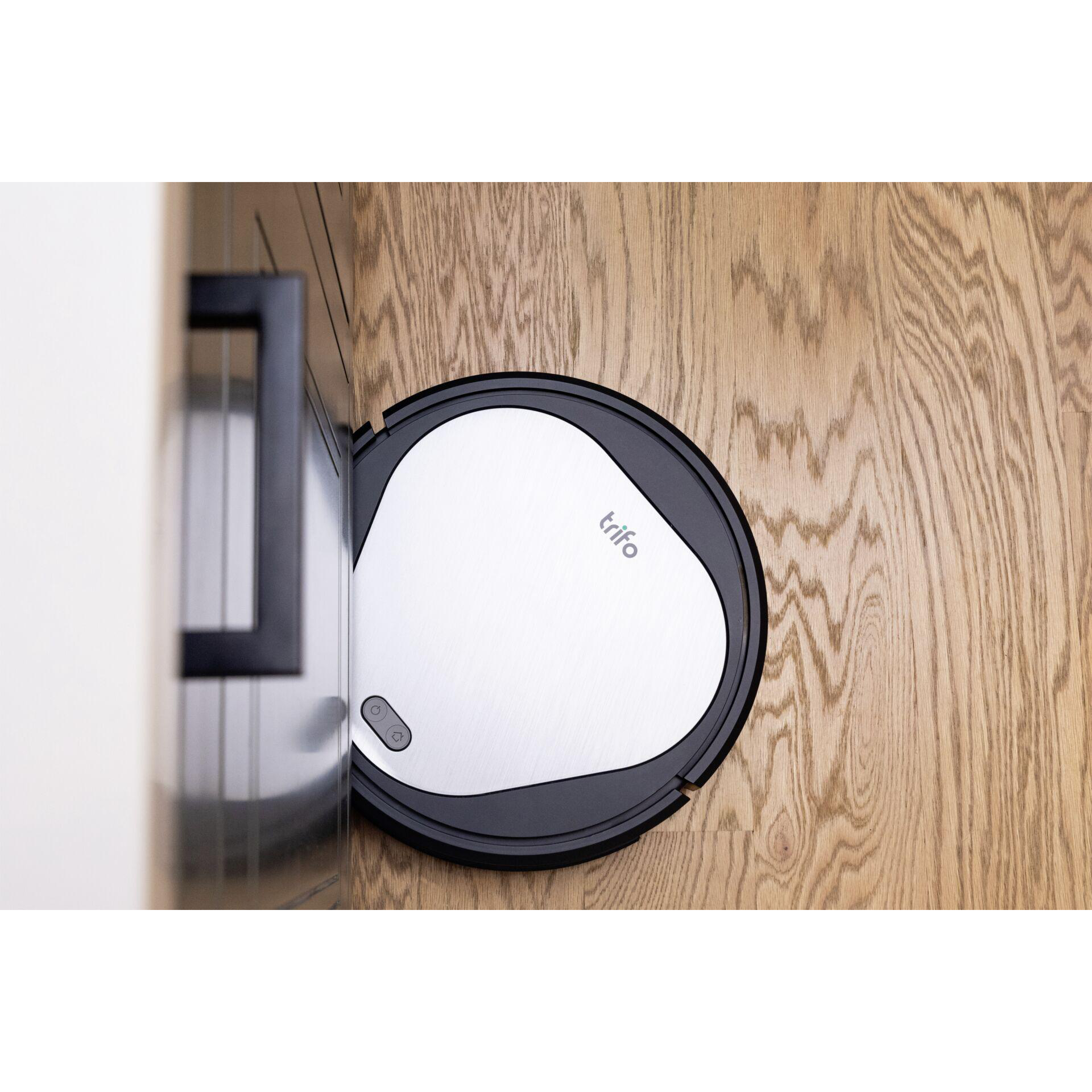 Roboter-Staubsauger auf Holzboden, in der Nähe des Schranks, schwarz und weiß.