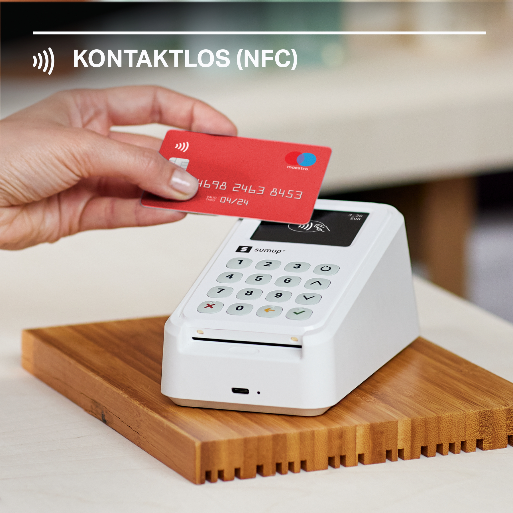Eine Hand hält eine rote Kreditkarte über ein weißes Zahlungsterminal. Der Text 'KONTAKTLOS (NFC)' steht darüber.