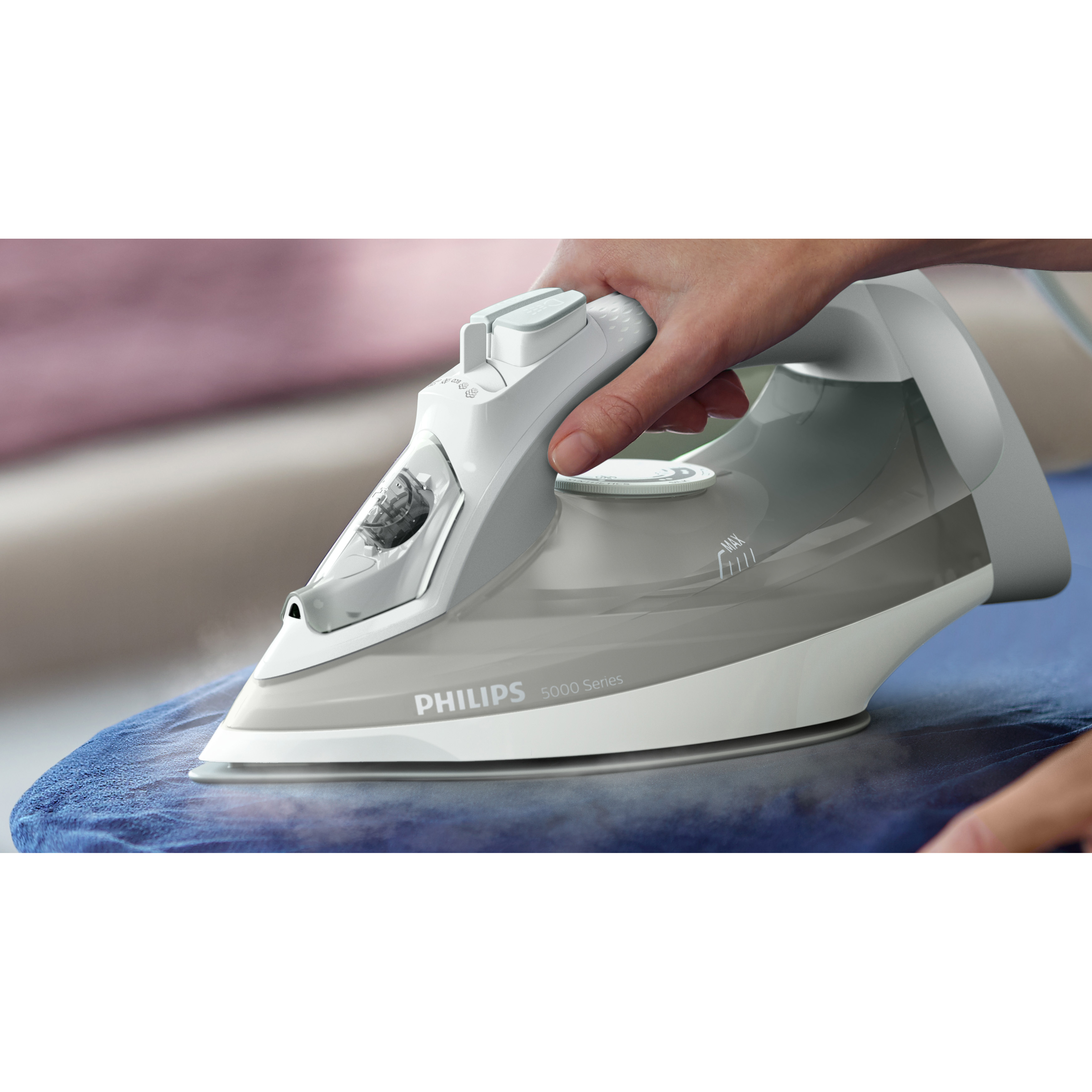 Eine Hand bügelt ein blaues Kleidungsstück mit einem weißen Philips-Bügeleisen.