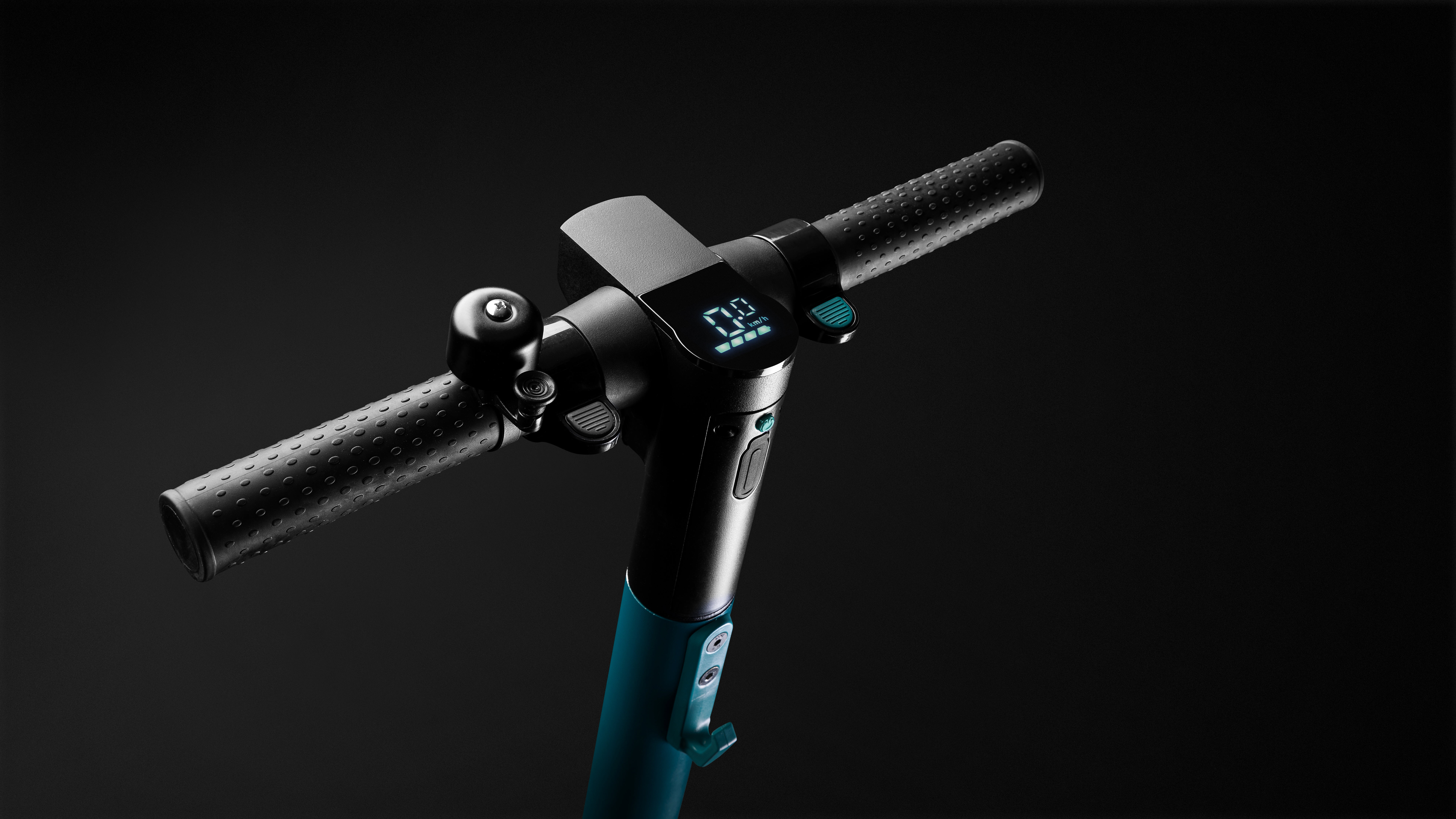 Nahaufnahme des Rollerlenkers mit Digitalanzeige, Klingel und schwarzen Gummihandgriffen.