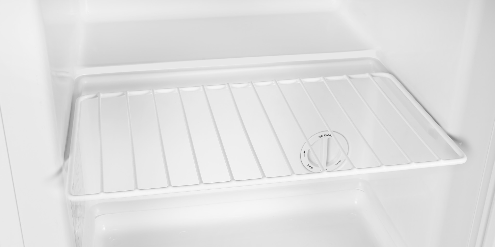 Weißer Kühlschrankinnenraum. Ein Regal und ein Knopf sind sichtbar.