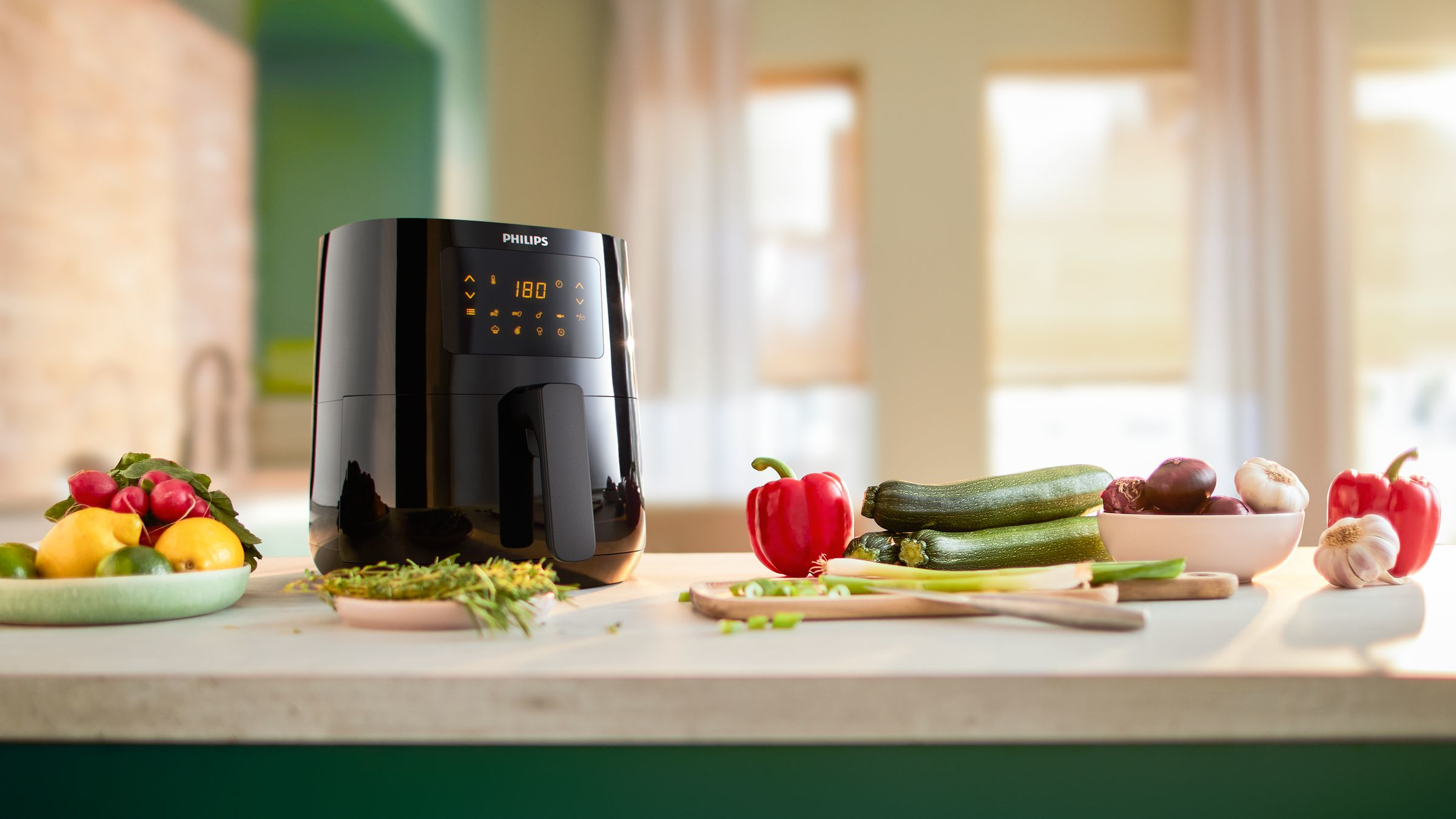 Friteuse à air avec des légumes sur un comptoir. La marque Philips est visible.