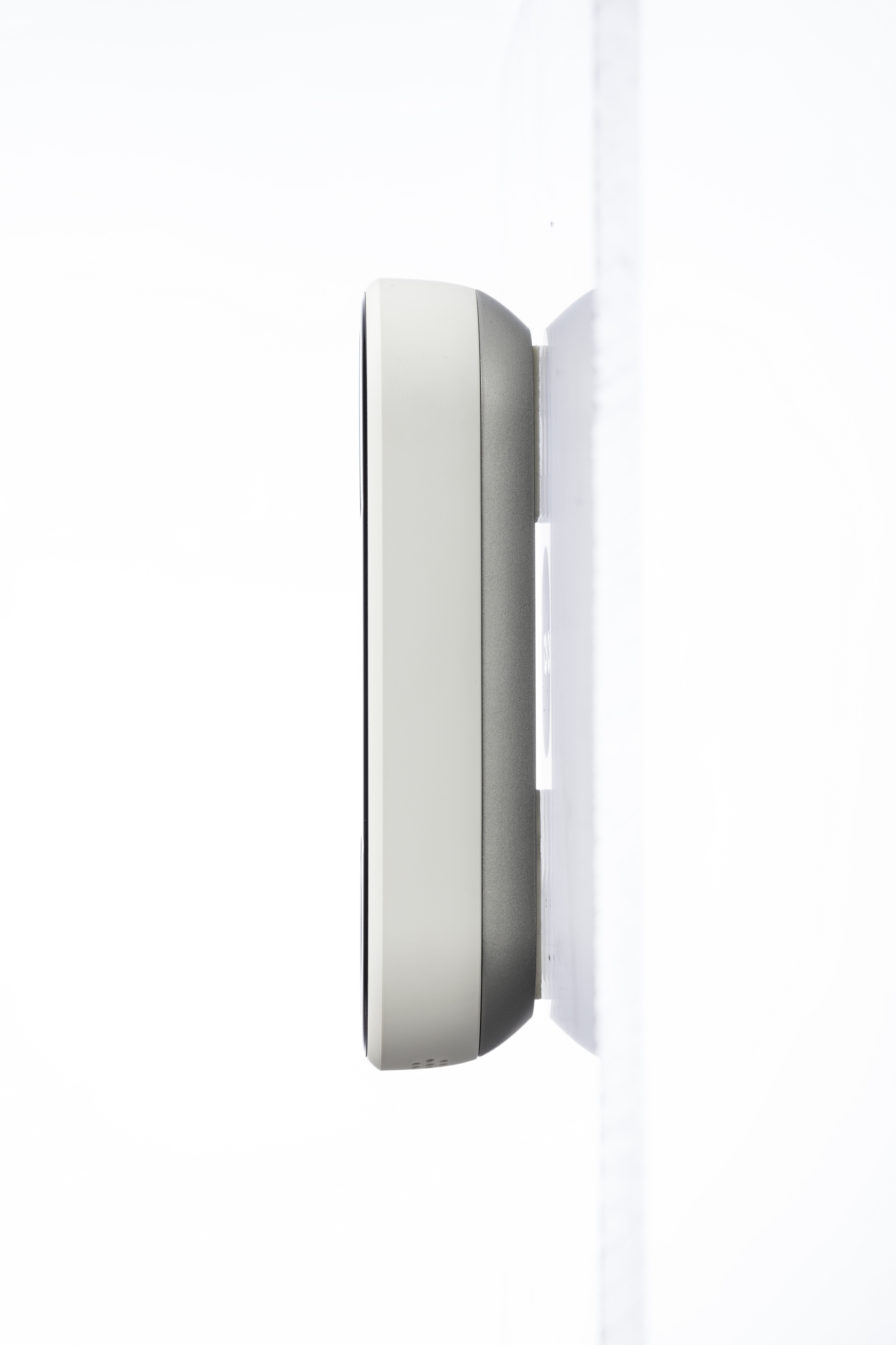 Seitenansicht eines Smart Home-Geräts an einer weißen Wand. Es ist ein weißes und graues Rechteck.