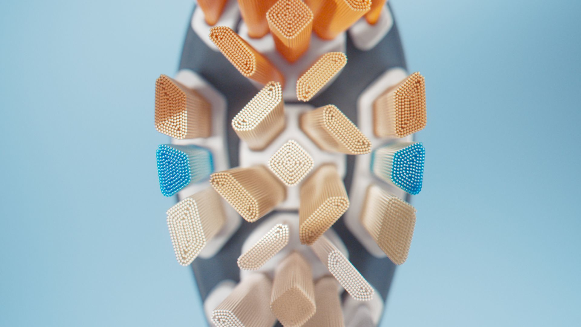 Close-up of a toothbrush head with various colored bristles: white, orange, beige, and blue.