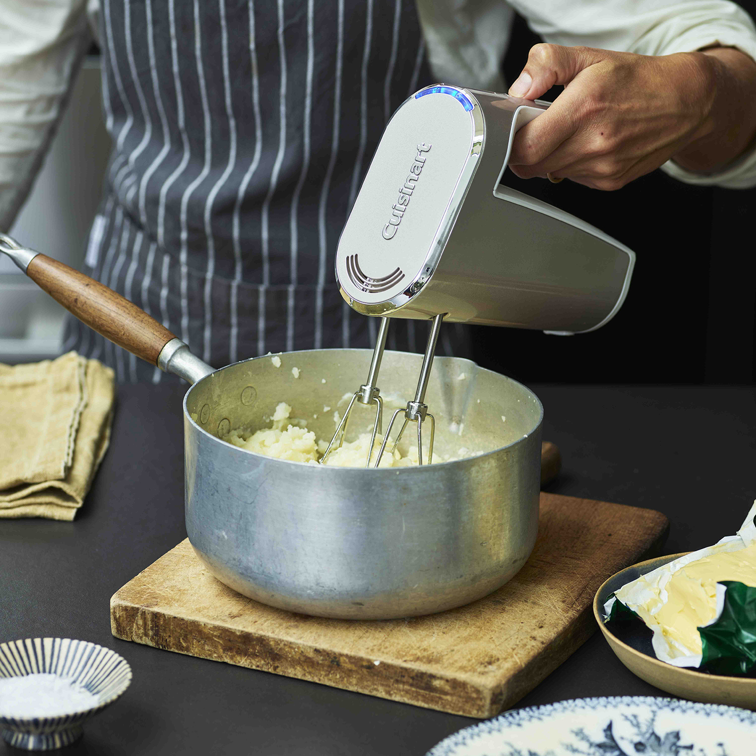 Persoon die aardappelpuree mengt met een elektrische mixer.