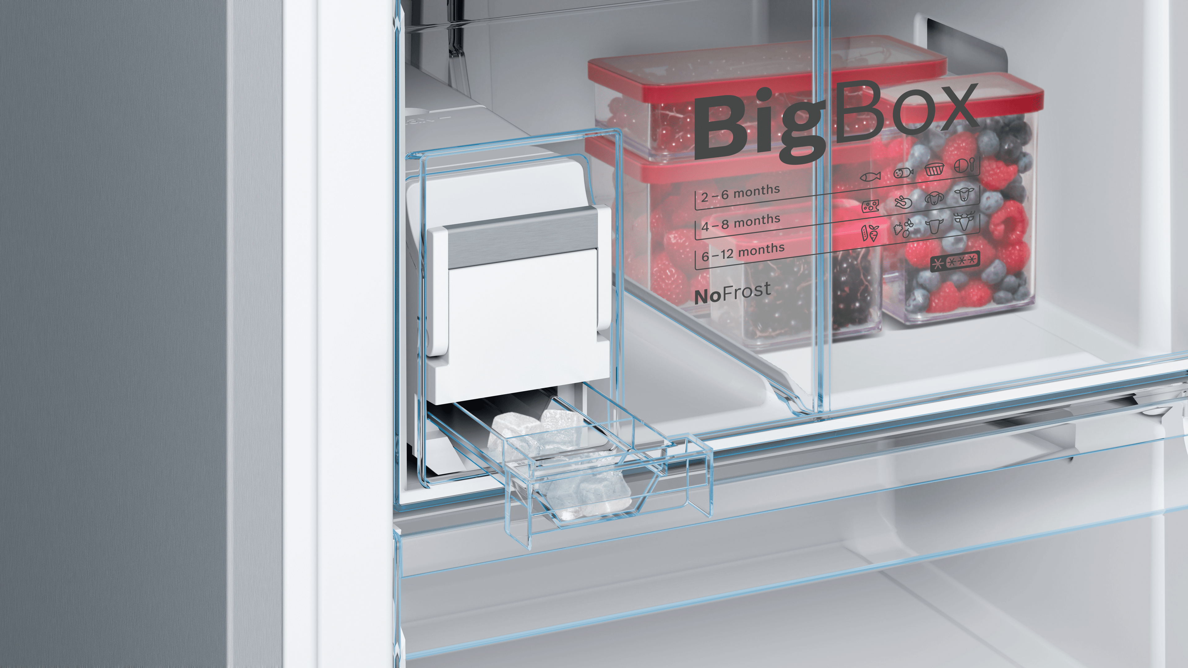 Buzdolabı içi: buz yapıcı, buz küpleri ve donmuş meyvelerle dolu iki kırmızı BigBox kabı.