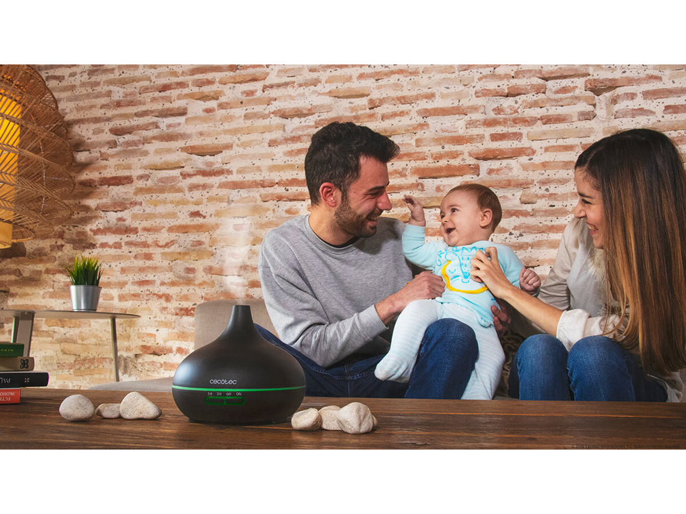 Familia con un bebé en un entorno doméstico con un difusor negro.