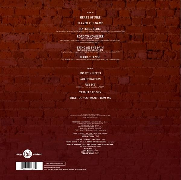 Albumcover mit Titelliste und Credits auf Backsteinmauer Hintergrund.