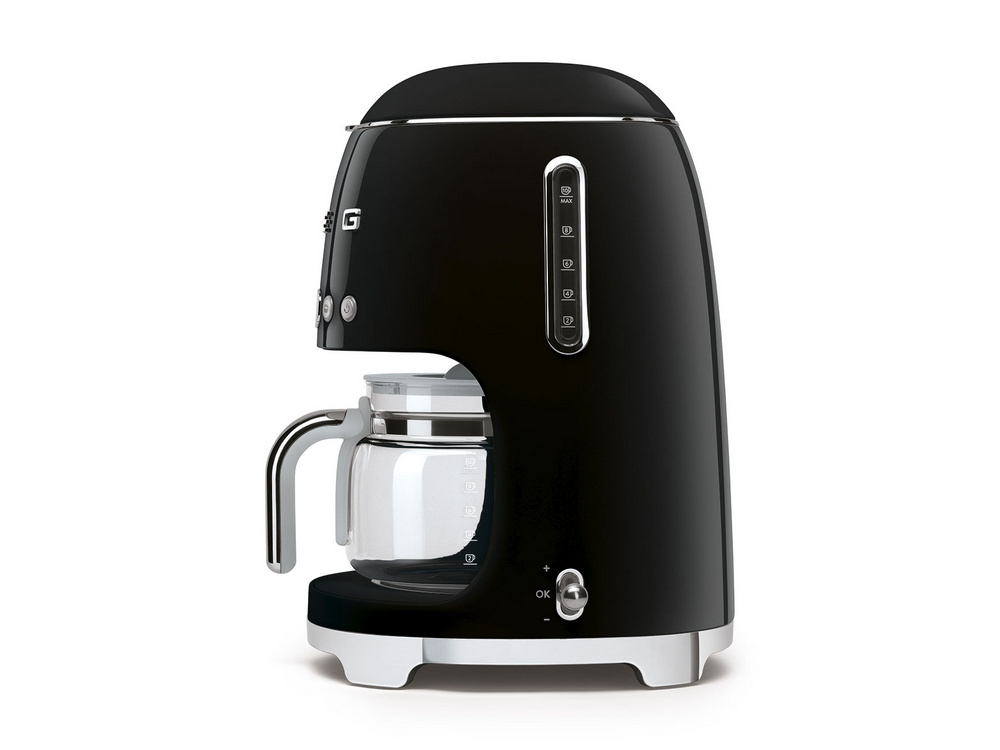 Cafetera Smeg negra con jarra de vidrio. Sobre superficie blanca, vista lateral.
