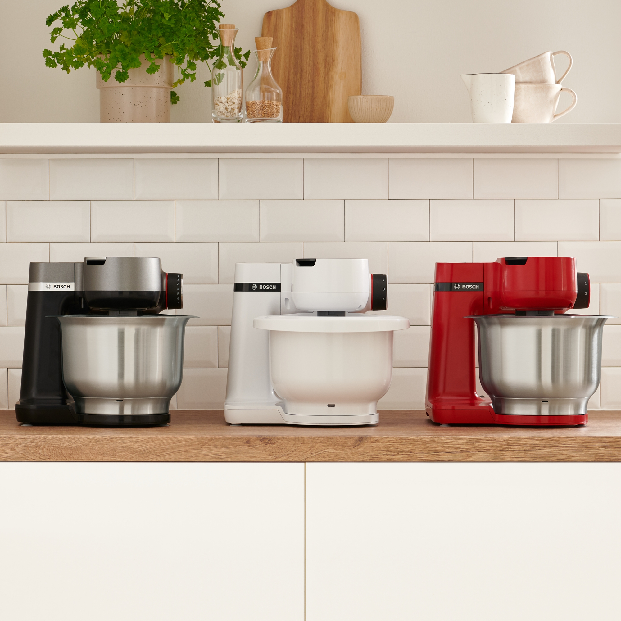 Tres batidoras Bosch en negro, blanco y rojo sobre una superficie de madera.