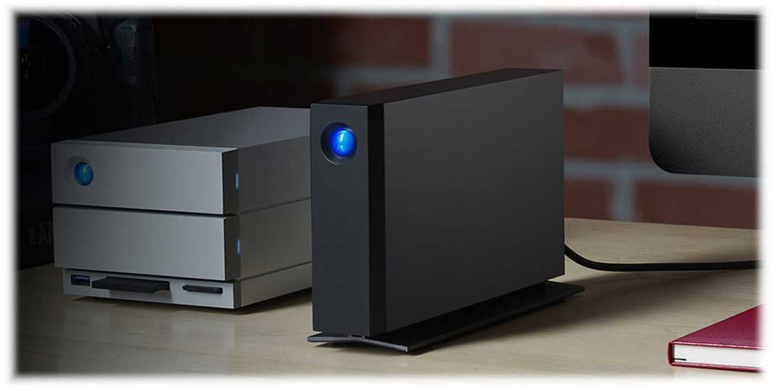 Deux disques durs externes, un noir et un argenté, sur un bureau en bois.