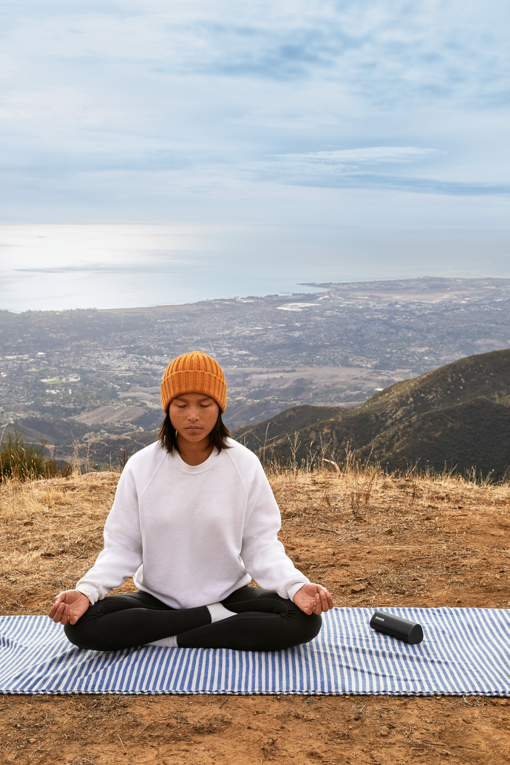 Een vrouw die mediteert op een mat in de bergen met een schilderachtig uitzicht.