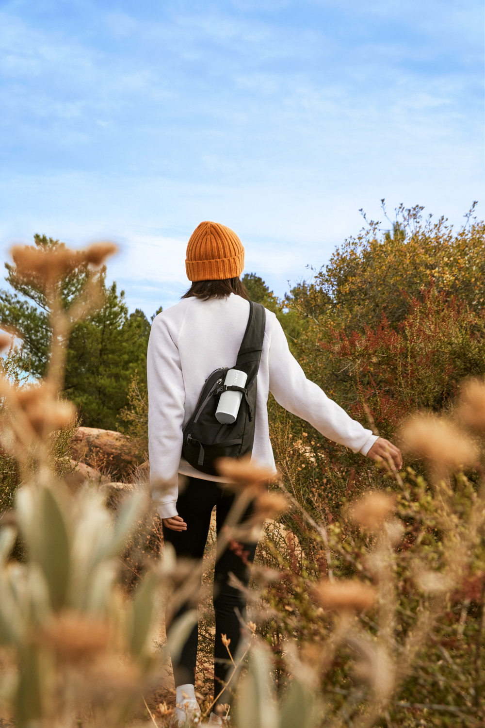 Personne marchant sur un sentier dans les bois, portant un chapeau et un sac à dos.