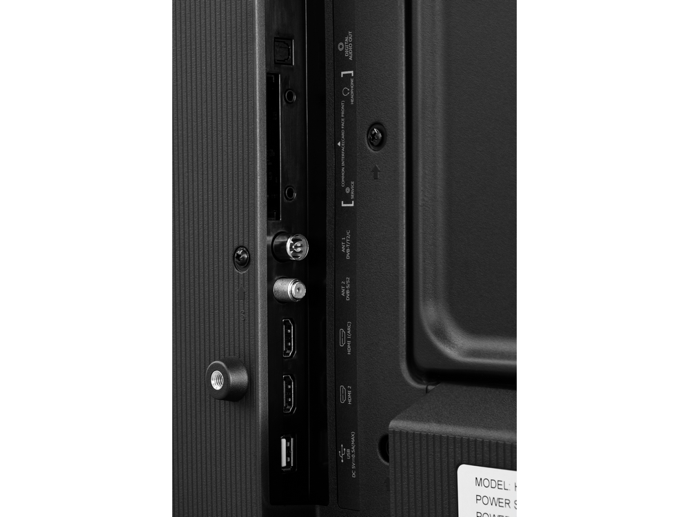 Vista trasera de un televisor negro con varios puertos, incluidos HDMI y USB, y orificios para tornillos.