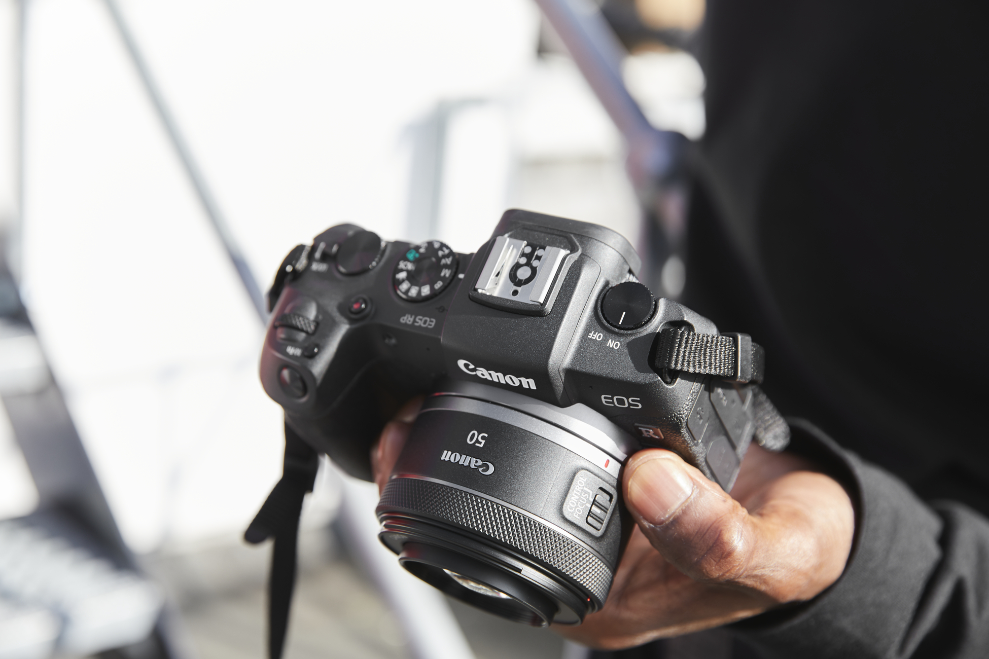 Person hält Canon-Kamera mit 50-mm-Objektiv.