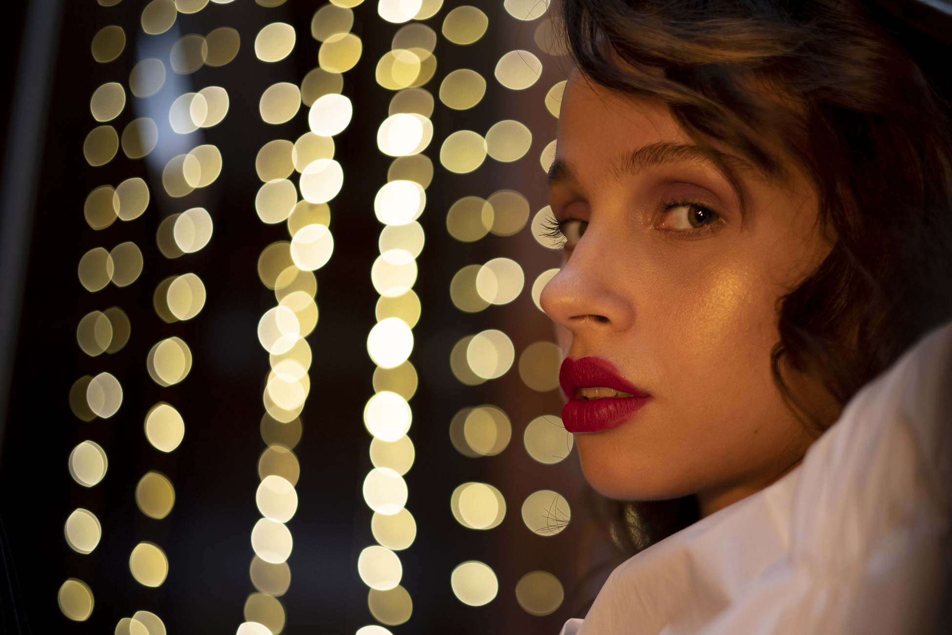 Frau mit rotem Lippenstift, Seitenprofil, mit Bokeh-Lichtern im Hintergrund.