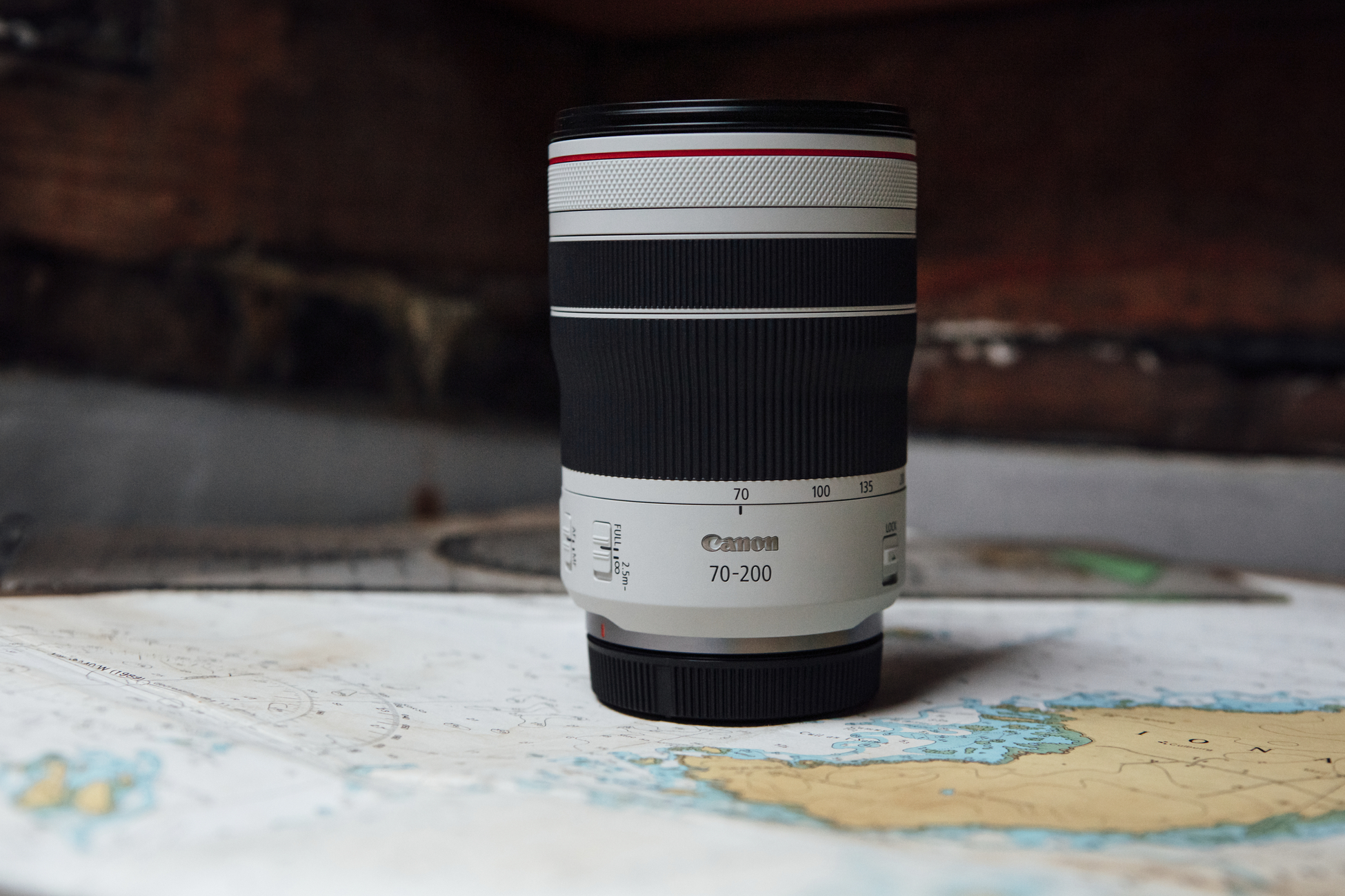 Canon 70-200mm Objektiv auf einer Karte. Das Objektiv ist weiß mit schwarzen und roten Akzenten.