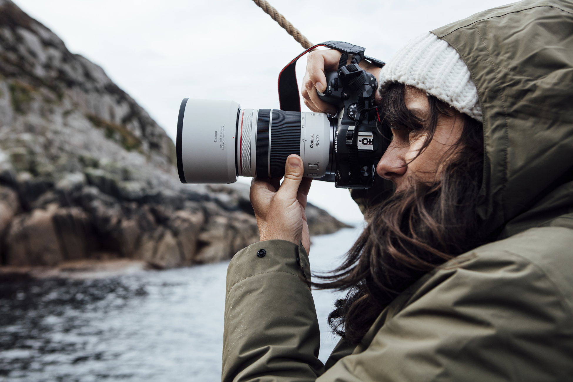 Person fotografiert mit Kamera in felsiger Küstenumgebung.