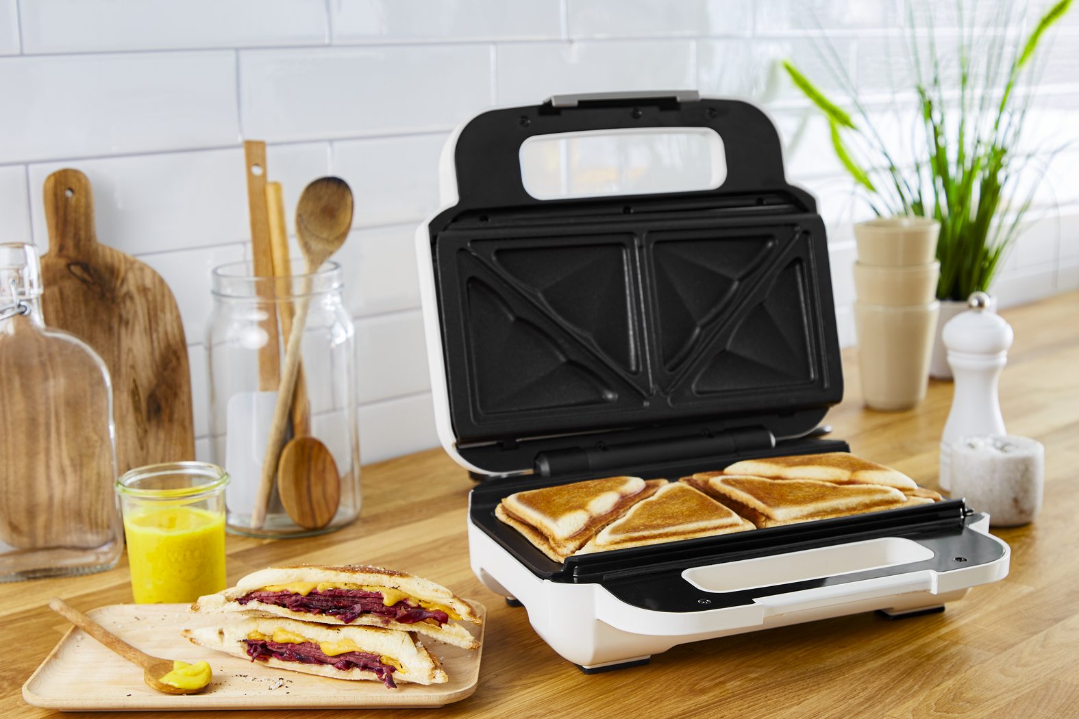 A sandwich maker with golden-brown toasted sandwiches, open on a counter.