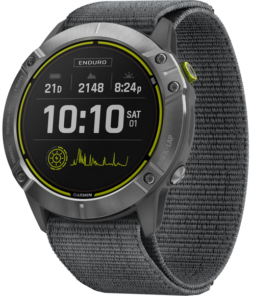 Egy Garmin Enduro óra szürke szíjjal. Az óralap időt, dátumot, akkumulátort és egyéb mérőszámokat mutat. Gombok láthatók az oldalon.