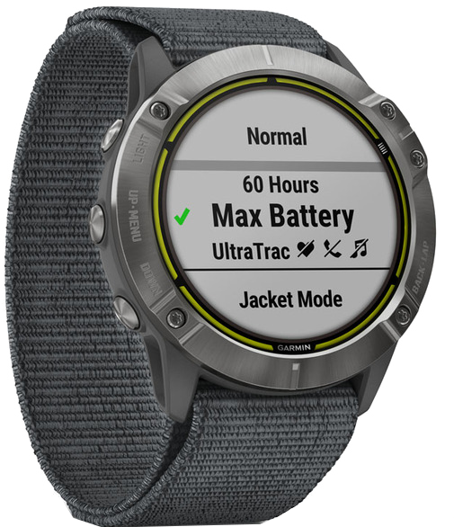 Egy Garmin okosóra a 'Max Battery'-t jeleníti meg zöld pipával. Az óra szürke szíjjal rendelkezik. Gombok és képernyő részletek láthatók.
