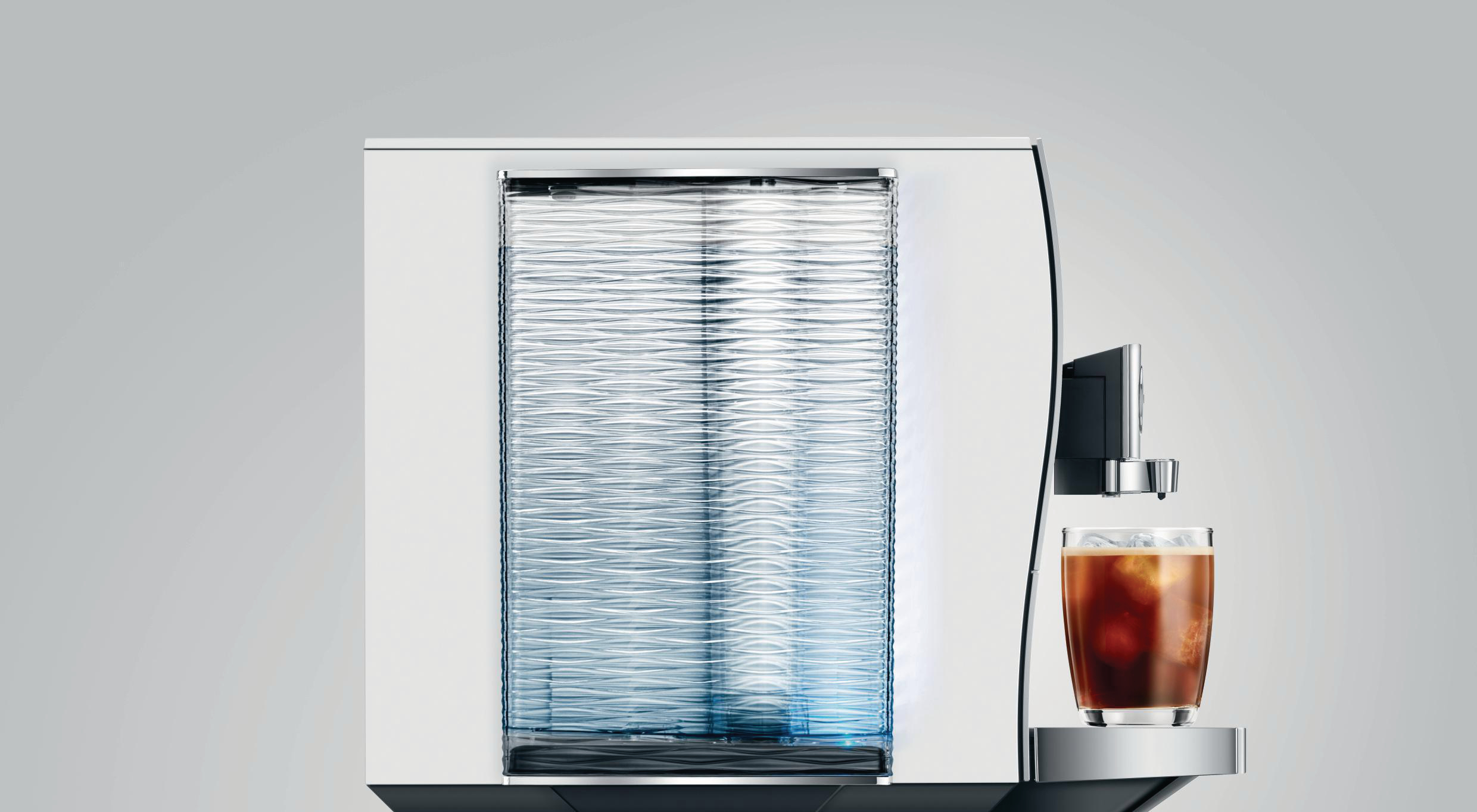 Moderne weiße Jura Kaffeemaschine mit einem Glas Eiskaffee auf einem silbernen Tablett.