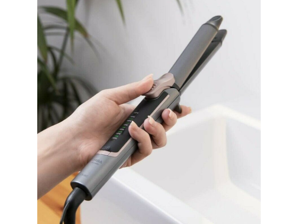 Una mano sosteniendo una plancha para el cabello, el producto es gris y negro, con fondo blanco.