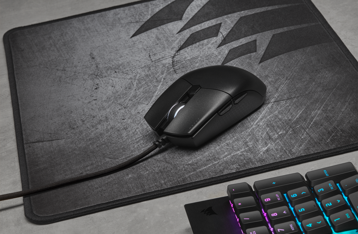 Schwarze Gaming-Maus auf einem grauen Mauspad, Tastatur im Hintergrund.