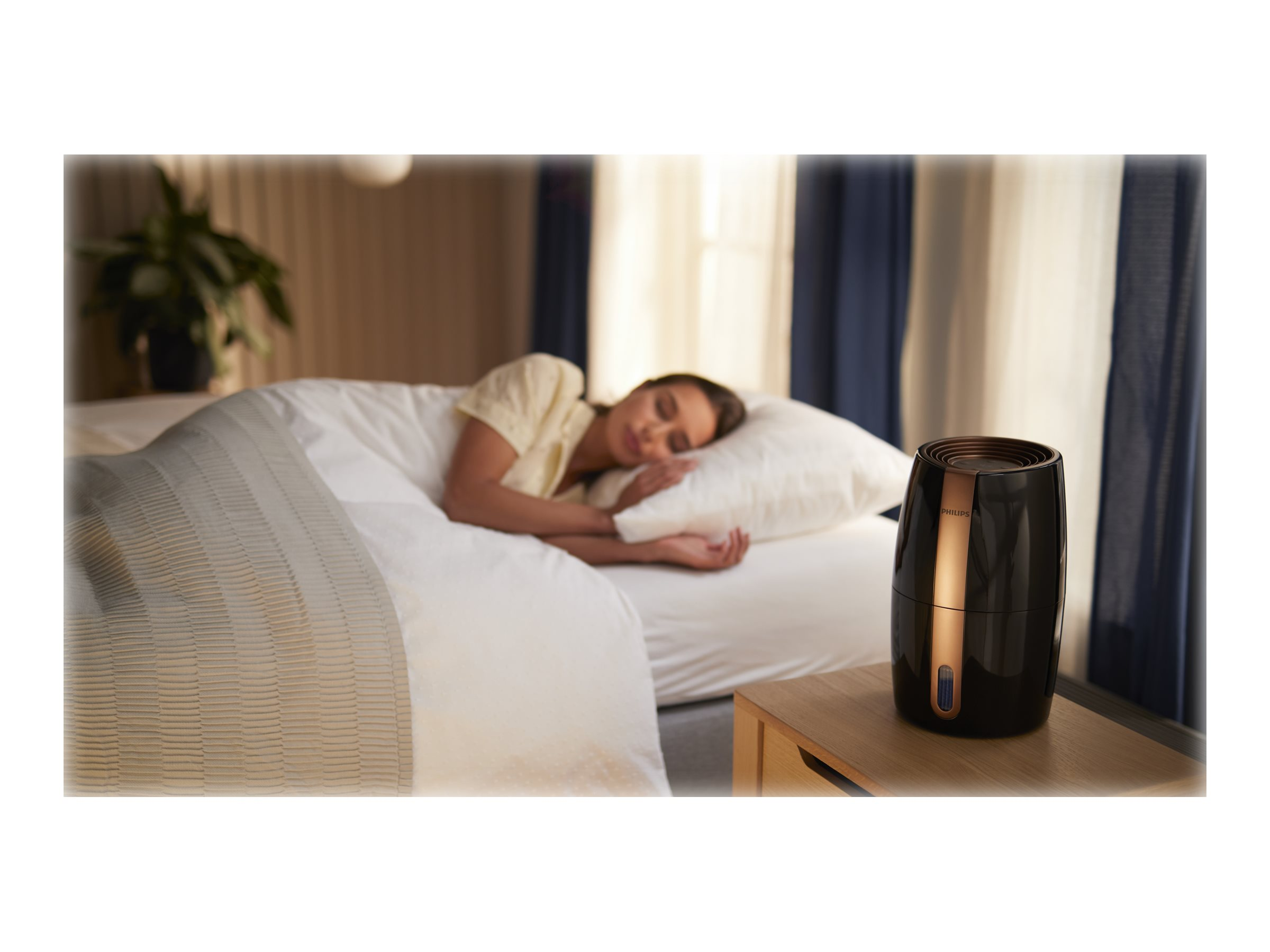 Una persona che dorme a letto con un umidificatore sul comodino accanto.