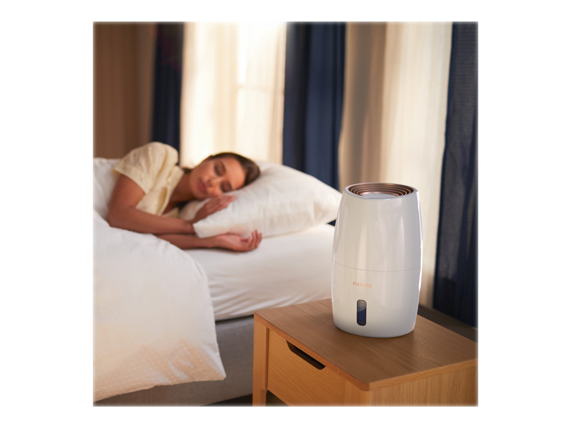Femme dormant près d'un humidificateur blanc sur une table de chevet.
