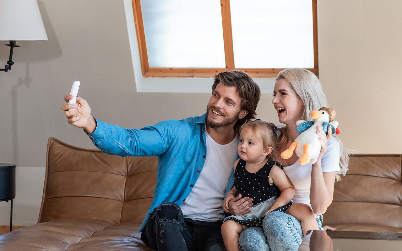 Familie macht Selfie auf einem Sofa.