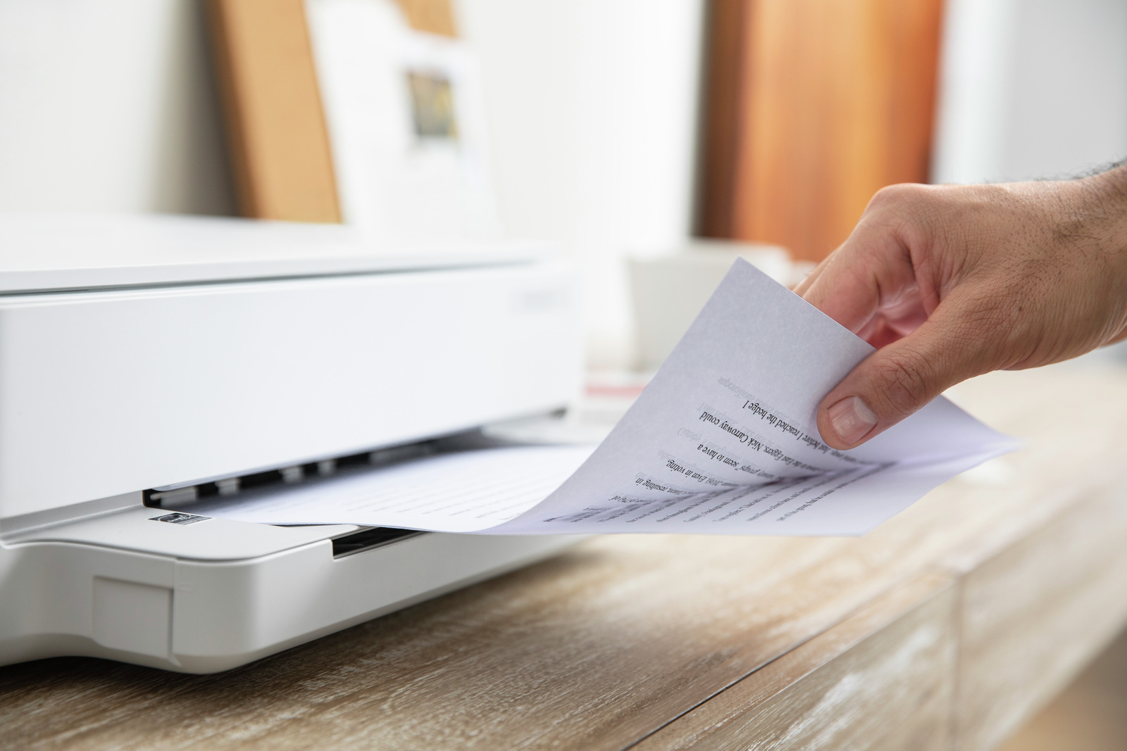 Mano tomando un papel impreso de una impresora blanca.