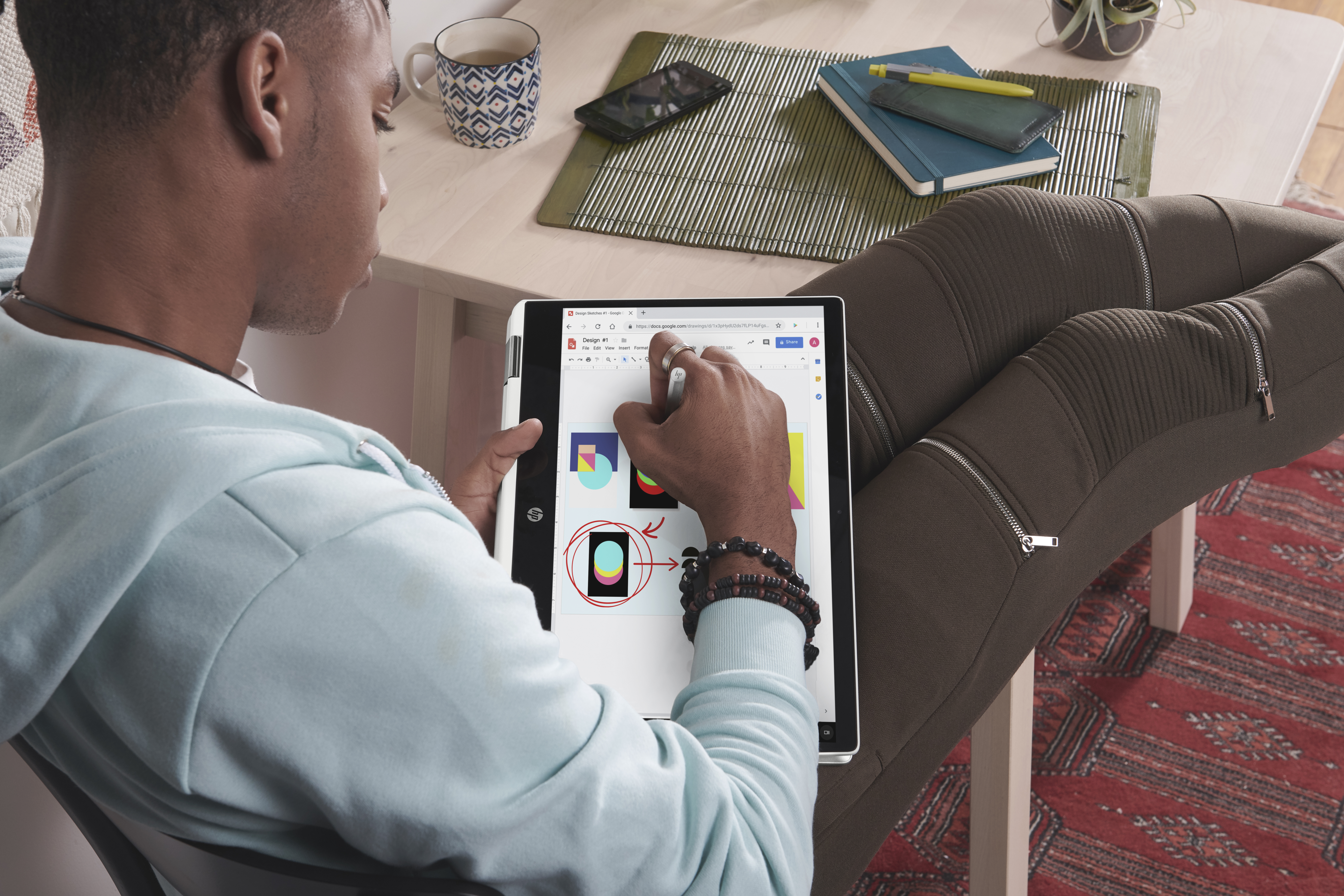 Mann benutzt Tablet, zeichnet Diagramme mit Stift. Telefon und Notizbuch auf dem Tisch.