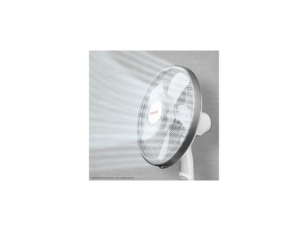 Un ventilador blanco soplando aire con un fondo gris.