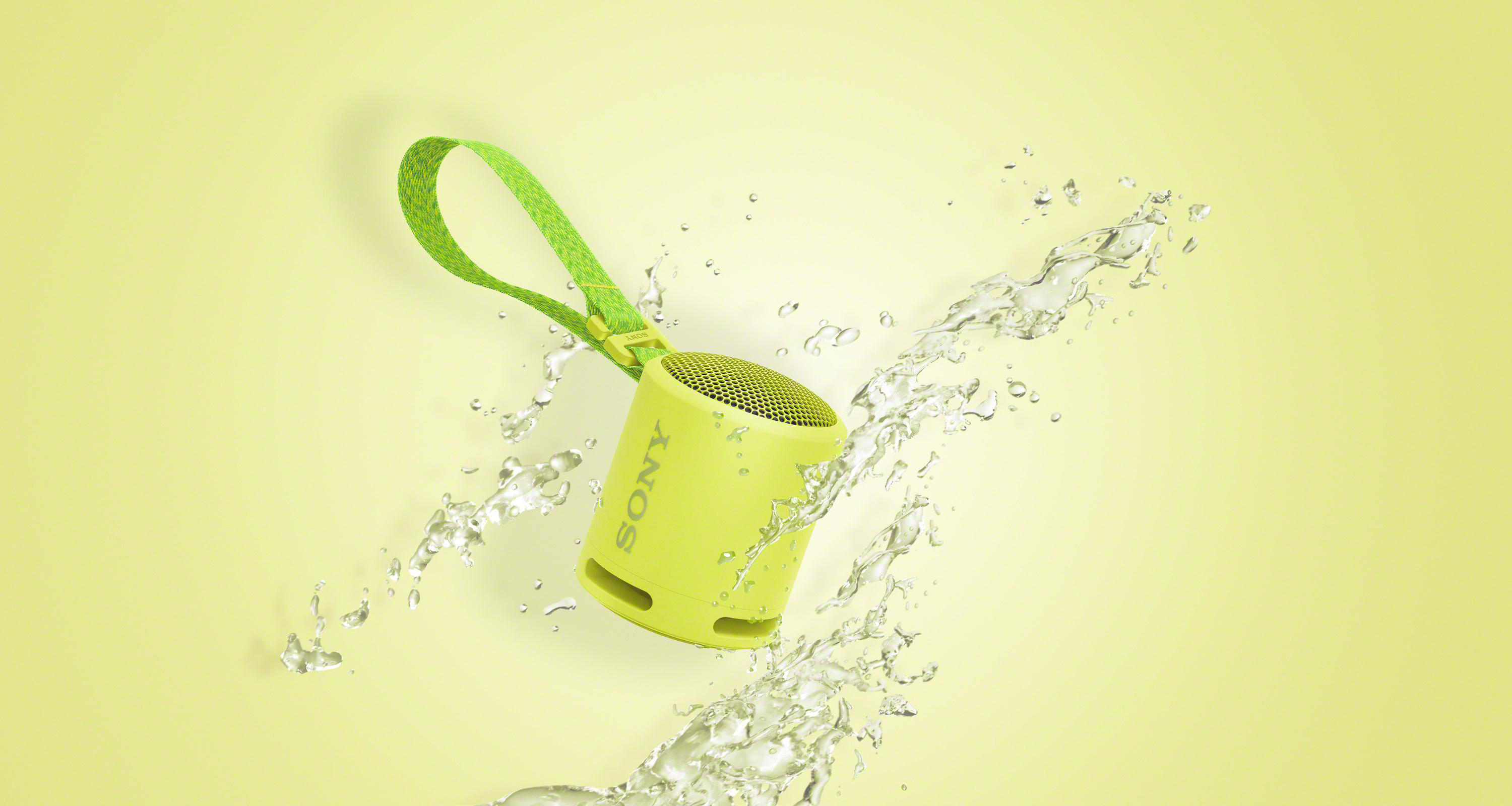 Gelber tragbarer Sony-Lautsprecher mit Wasserspritzern auf gelbem Hintergrund.