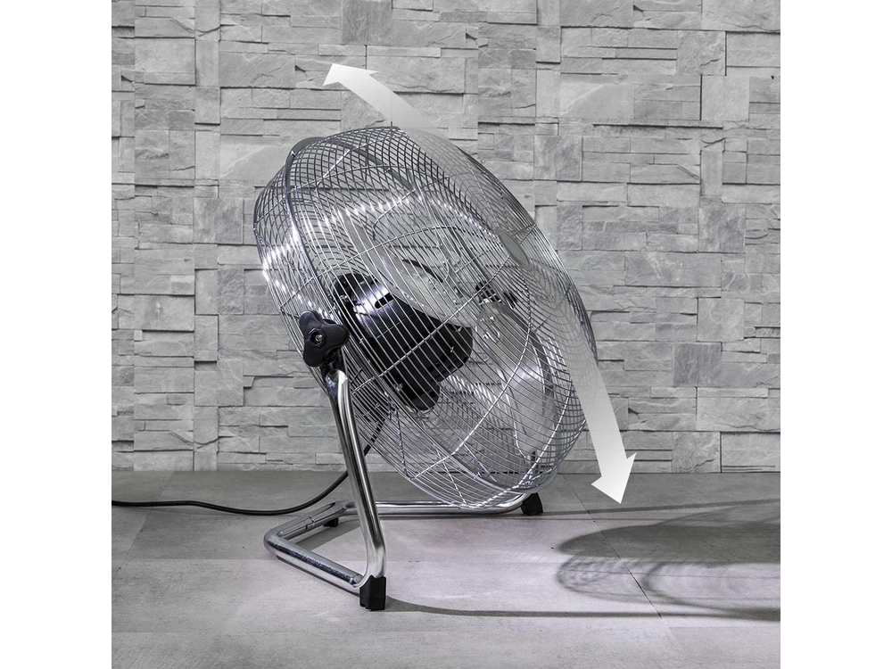 Ventilador de metal plateado con jaula, inclinado, flecha indicando la dirección.