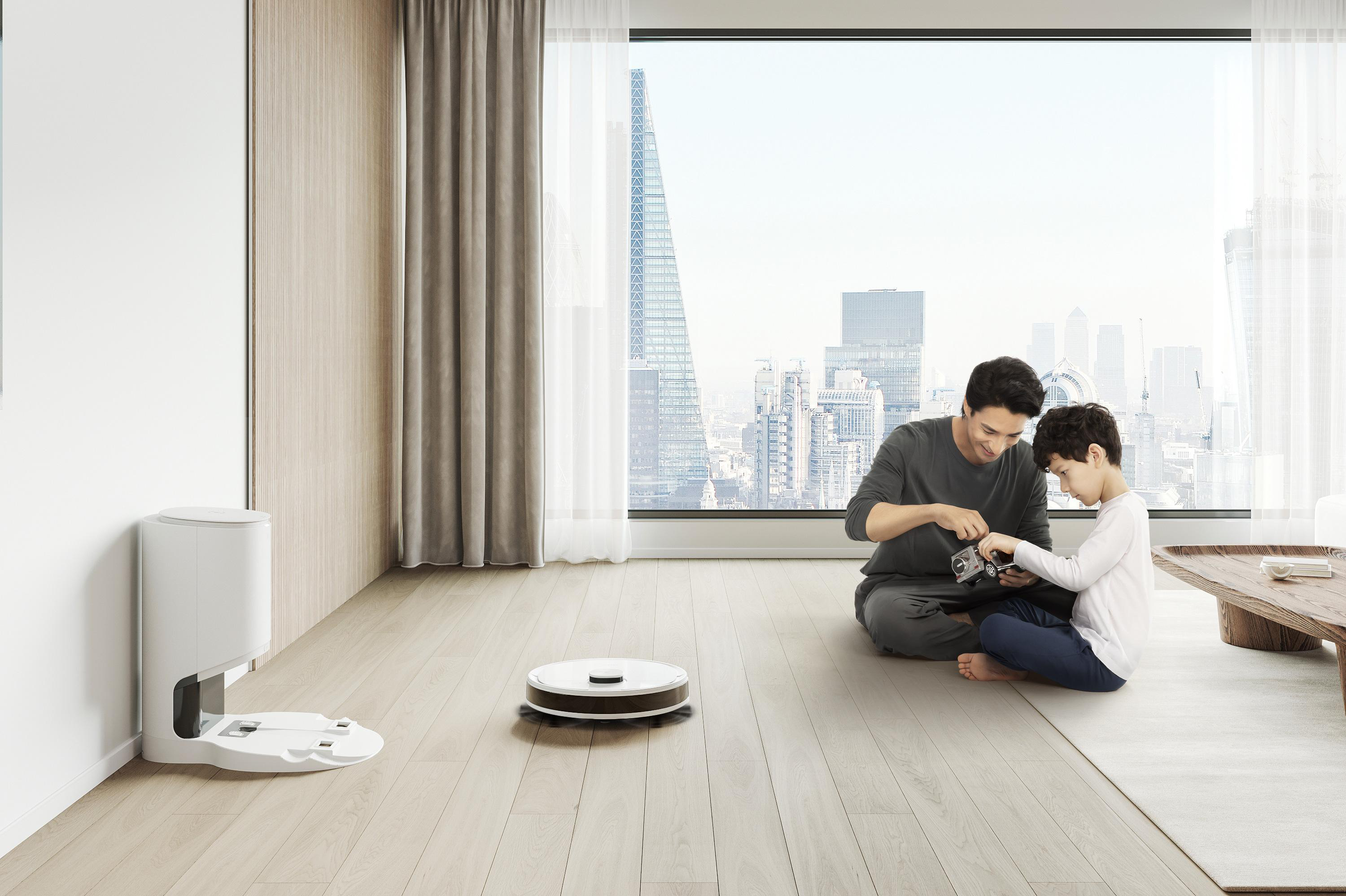 Vater und Sohn auf dem Boden mit Roboter-Staubsauger und Dockingstation, Fensterblick.