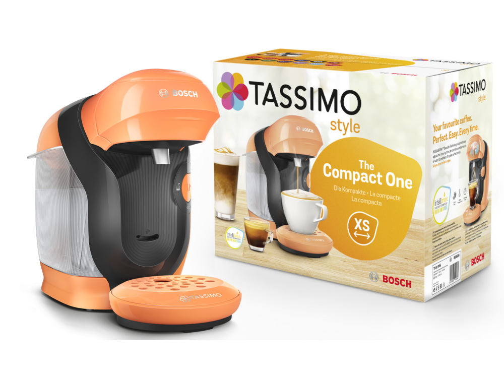 Una cafetera Tassimo naranja y negra junto a su caja de producto, mostrando una imagen de taza de café.