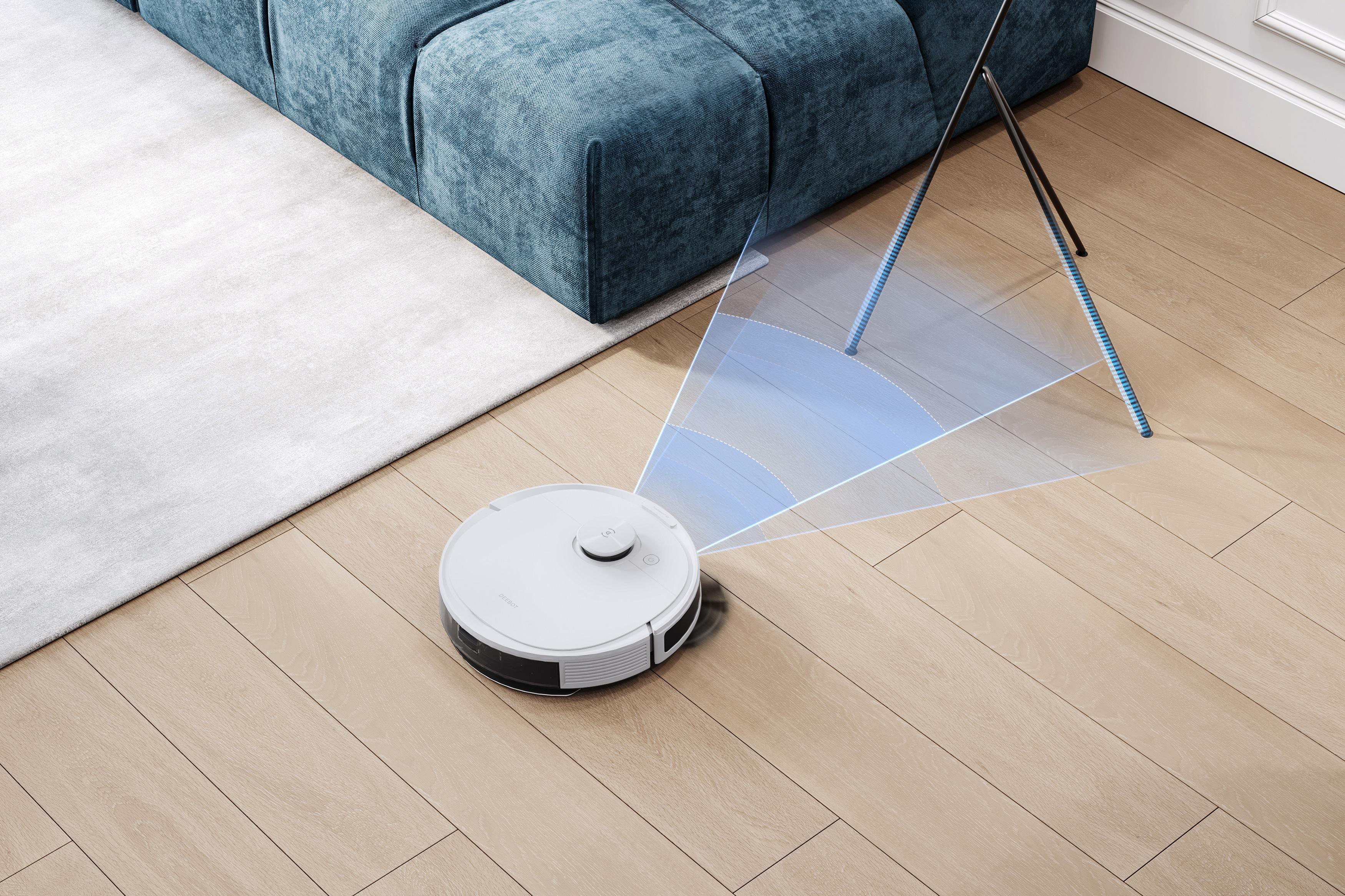 Roboter-Staubsauger auf Holzboden neben Sofa. Blaue Lichtbögen zeigen Reinigungsweg.