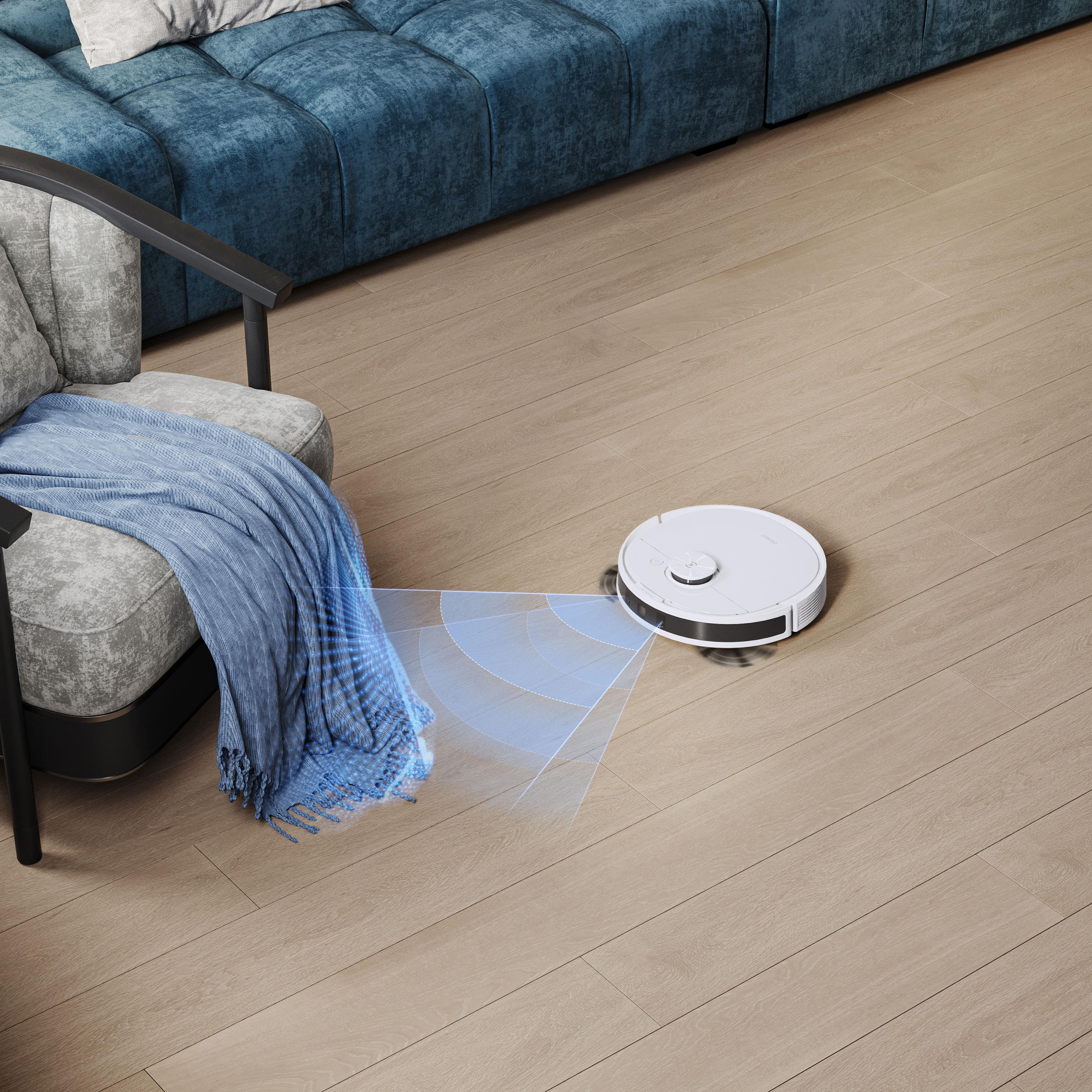 Roboter-Staubsauger reinigt Holzboden. Sofa und Stuhl im Hintergrund. Blaue Decke auf dem Stuhl.