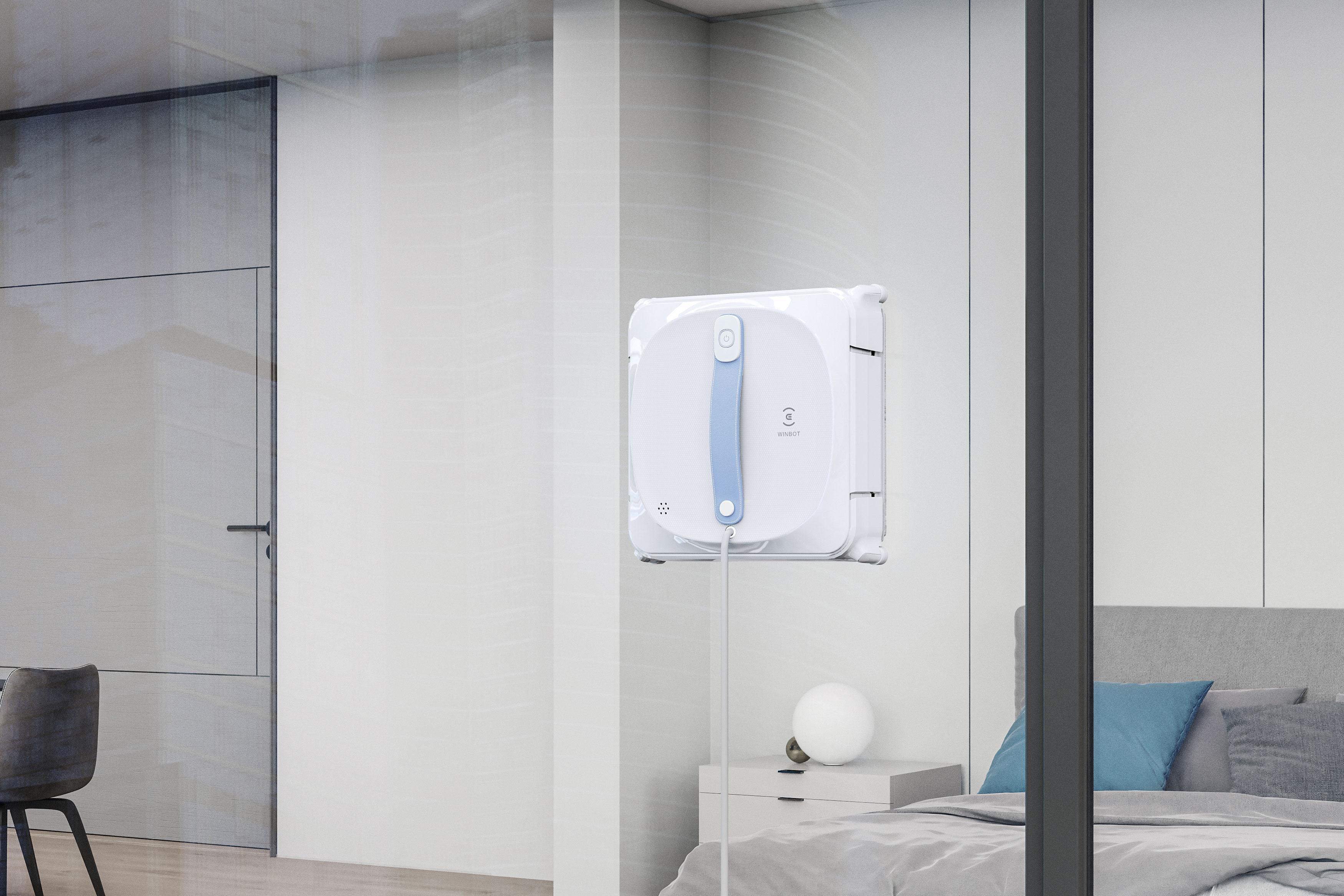 Fensterputzroboter an einem Glas, mit Schlafzimmer im Hintergrund.