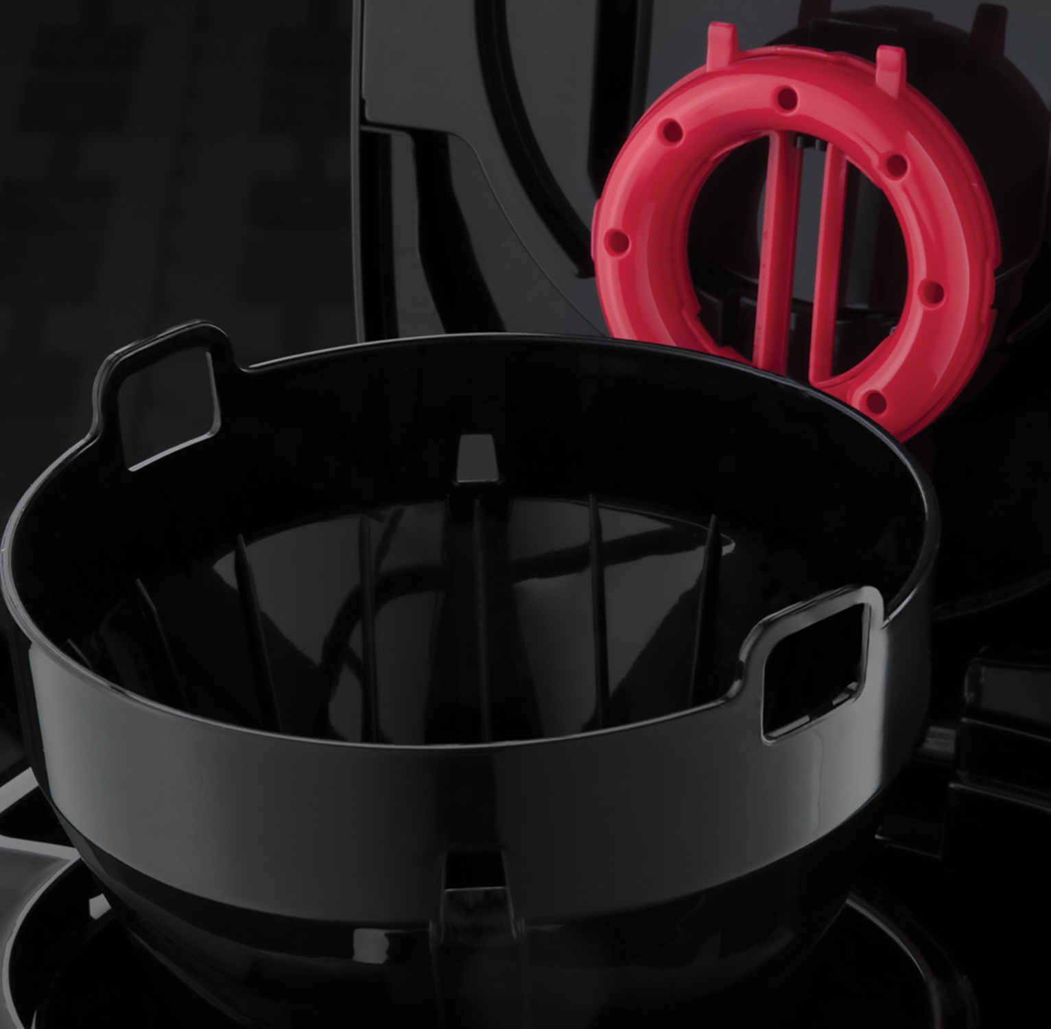 Black coffee maker parts, including a filter basket and a red ring.
