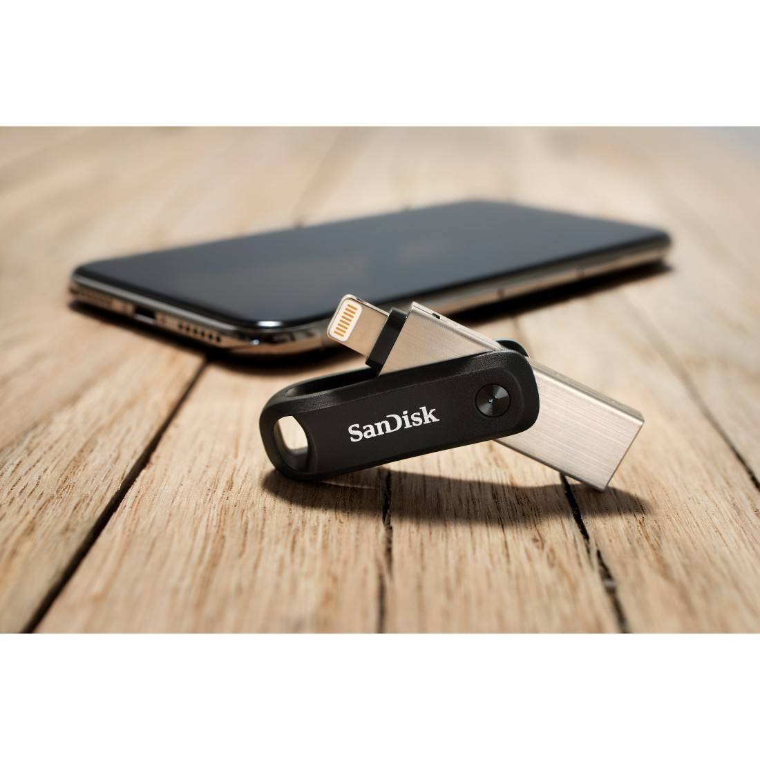 SanDisk USB-Laufwerk, das mit einem Telefon verbunden ist, auf einem Holztisch.