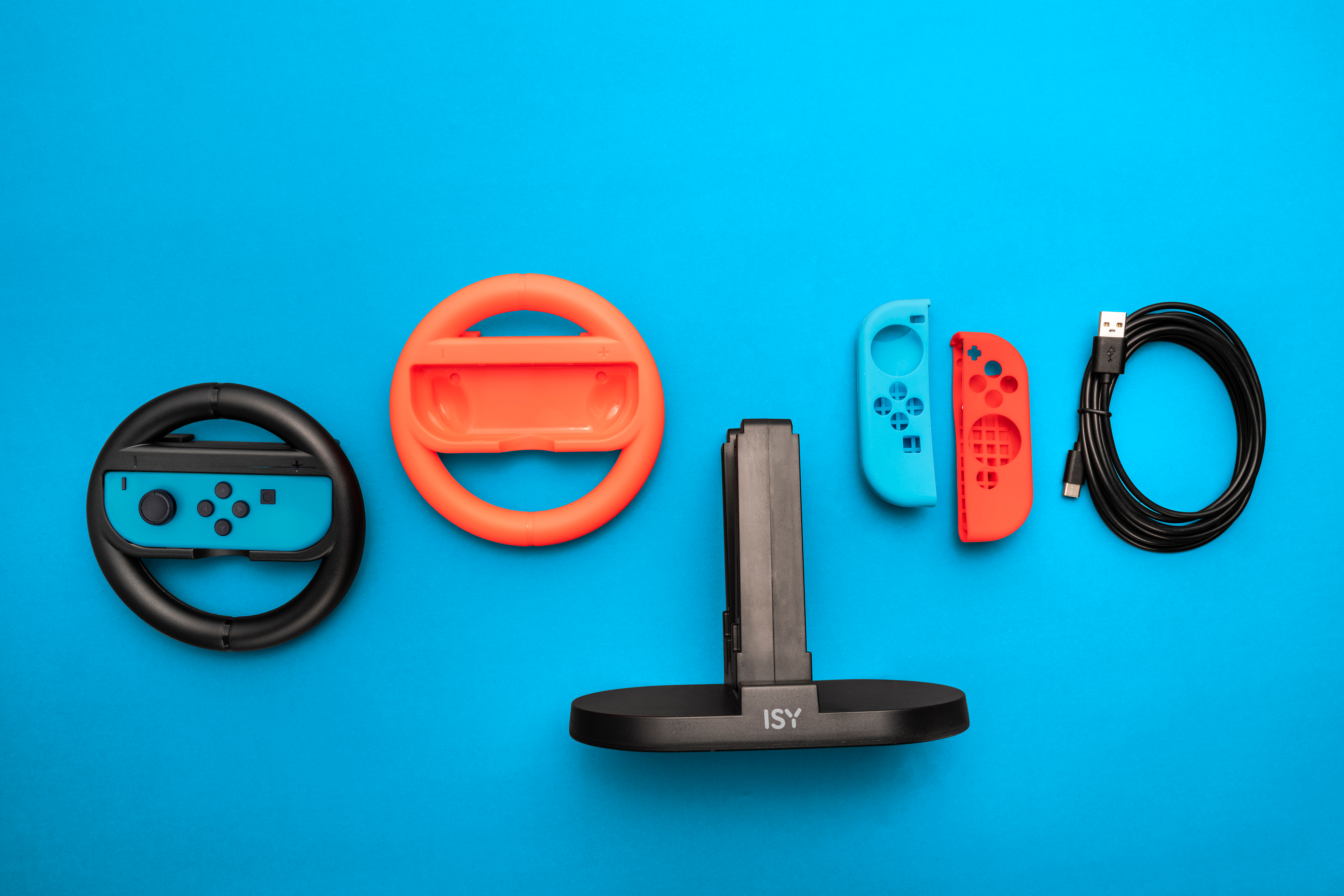 Accessori di gioco su sfondo blu: un volante, controller e una stazione di ricarica con cavo.