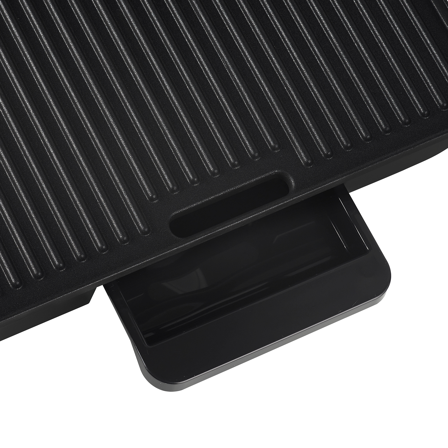Close-up of a black grill with ridges and a small tray on the bottom right.