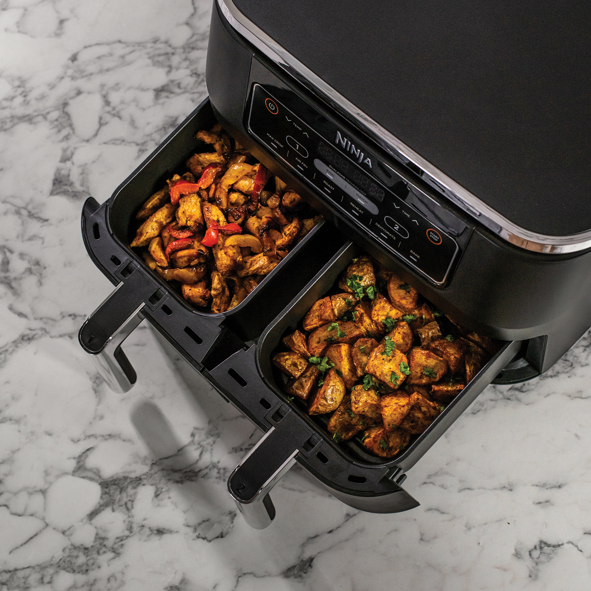 Ninja airfryer met twee compartimenten, elk gevuld met gekookt voedsel.