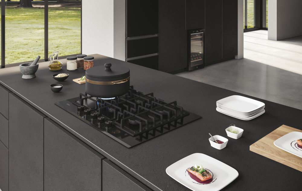 Una isla de cocina con una encimera negra, ollas y platos.
