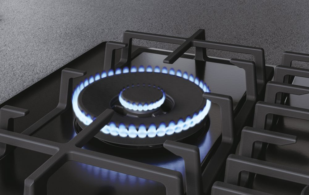 Cocina de gas con llamas. Encimera negra con rejillas negras. Llamas azules.